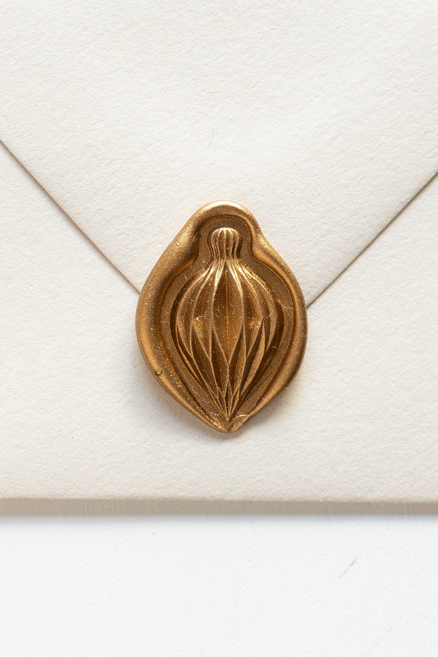 A beige envelope showcasing a gold paper ornament wax seal, perfect for the Holiday greeting cards