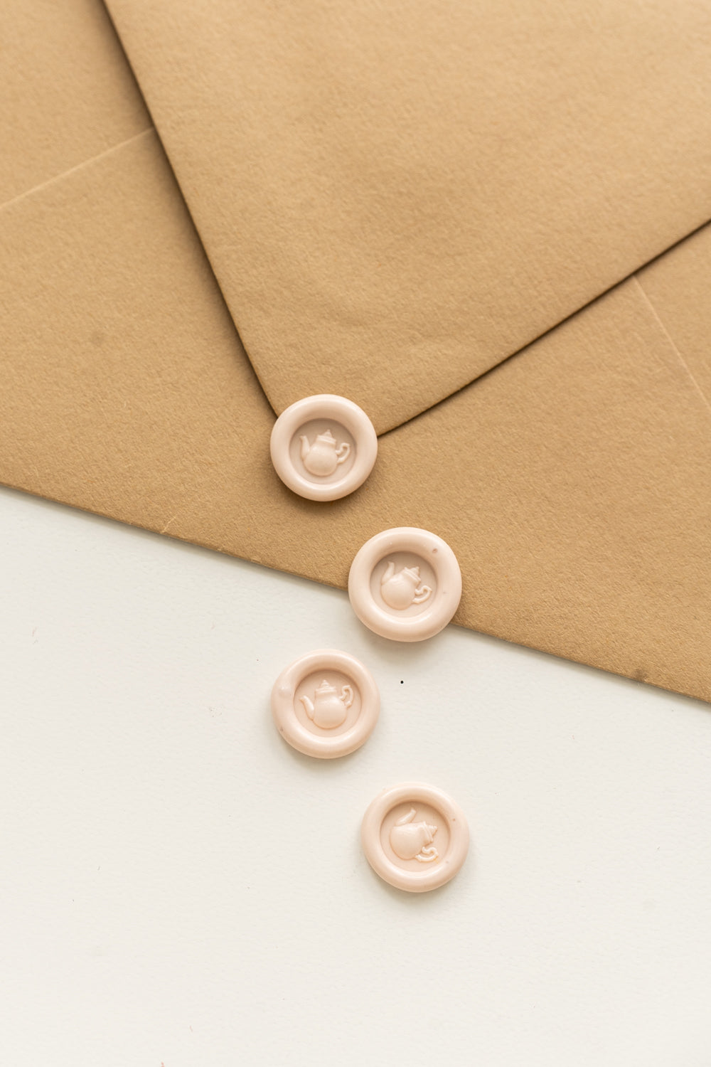 4 blush mini wax seals with a 3D tea pot design on a kraft envelope and white surface