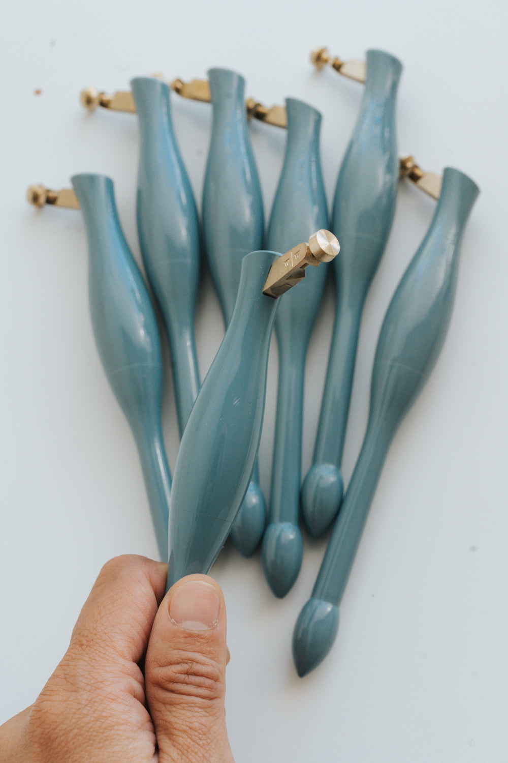 Set of blue calligraphy pens with a hand holding one, on a white background