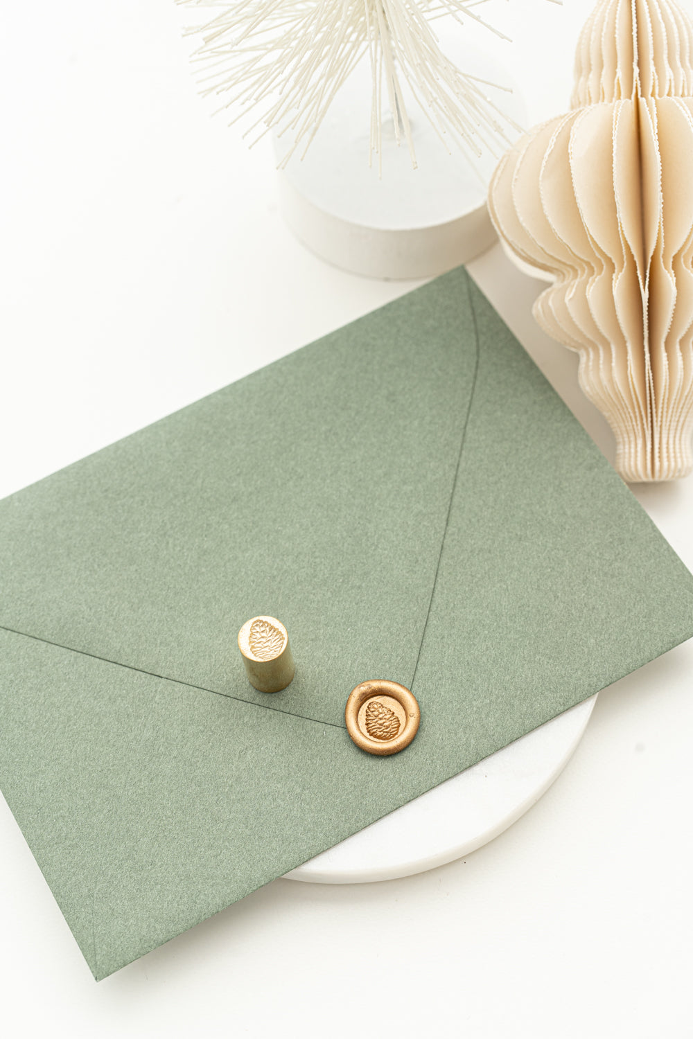 Gold pinecone wax seal on green envelope for holiday cards and Christmas stationery