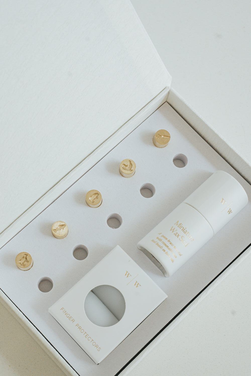 5 mini brass wax seal stamp heads featuring a cow, pig, carrot, chicken, and fish designs, neatly arranged in a keepsake white box with finger protectors and stamp handle