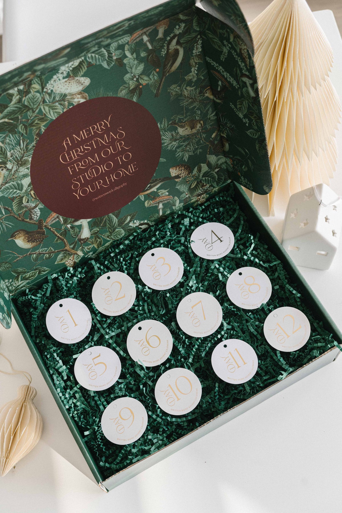 12 Days of Christmas advent calendar box open with numbered tags and green crinkle paper filling