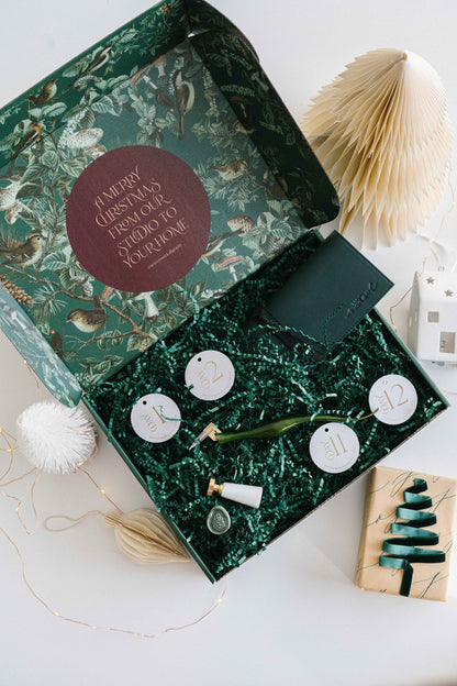 Calligraphy and wax seal tools inside holiday advent calendar box with festive packaging and decor