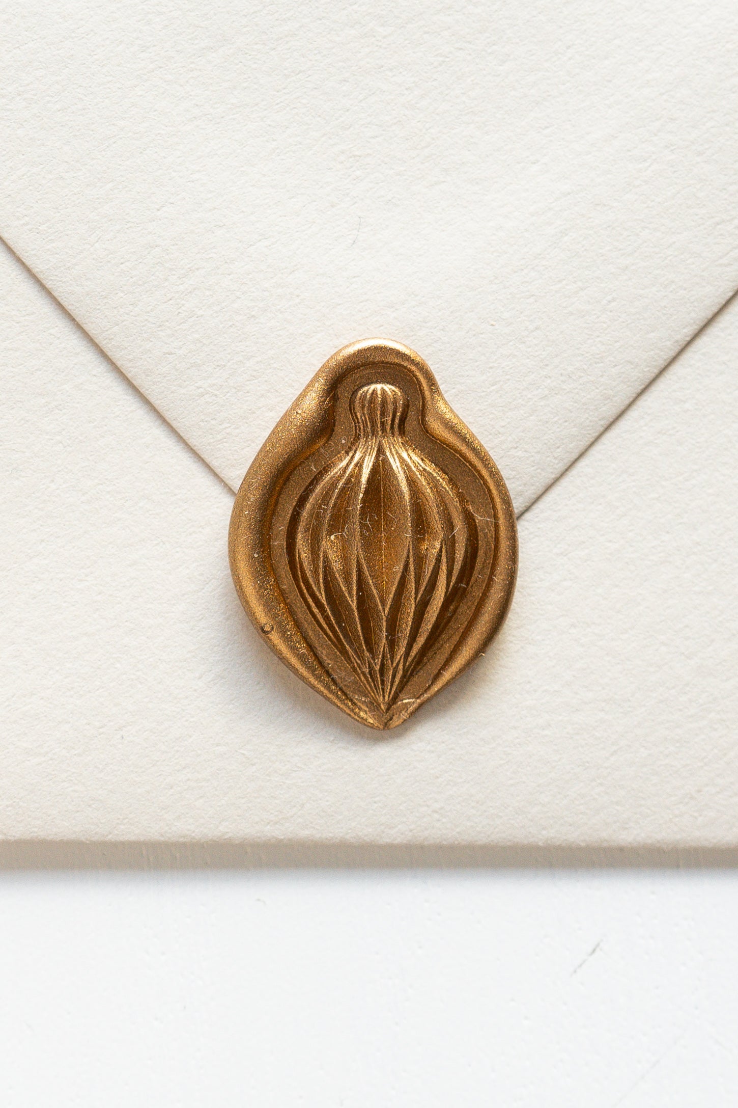 A beige envelope showcasing a gold paper ornament wax seal, perfect for the Holiday greeting cards