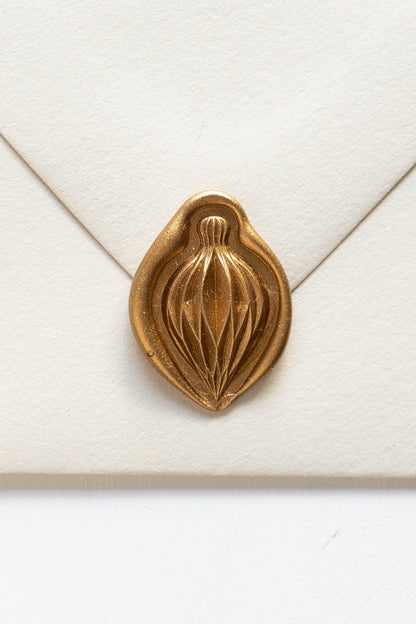A beige envelope showcasing a gold paper ornament wax seal, perfect for the Holiday greeting cards