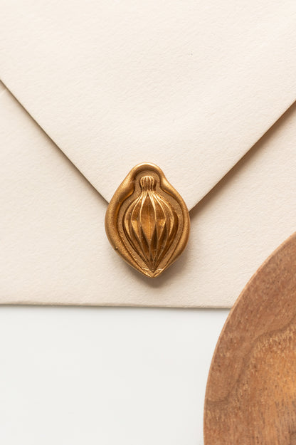 A beige envelope showcasing a gold paper ornament wax seal, perfect for Holiday greeting cards