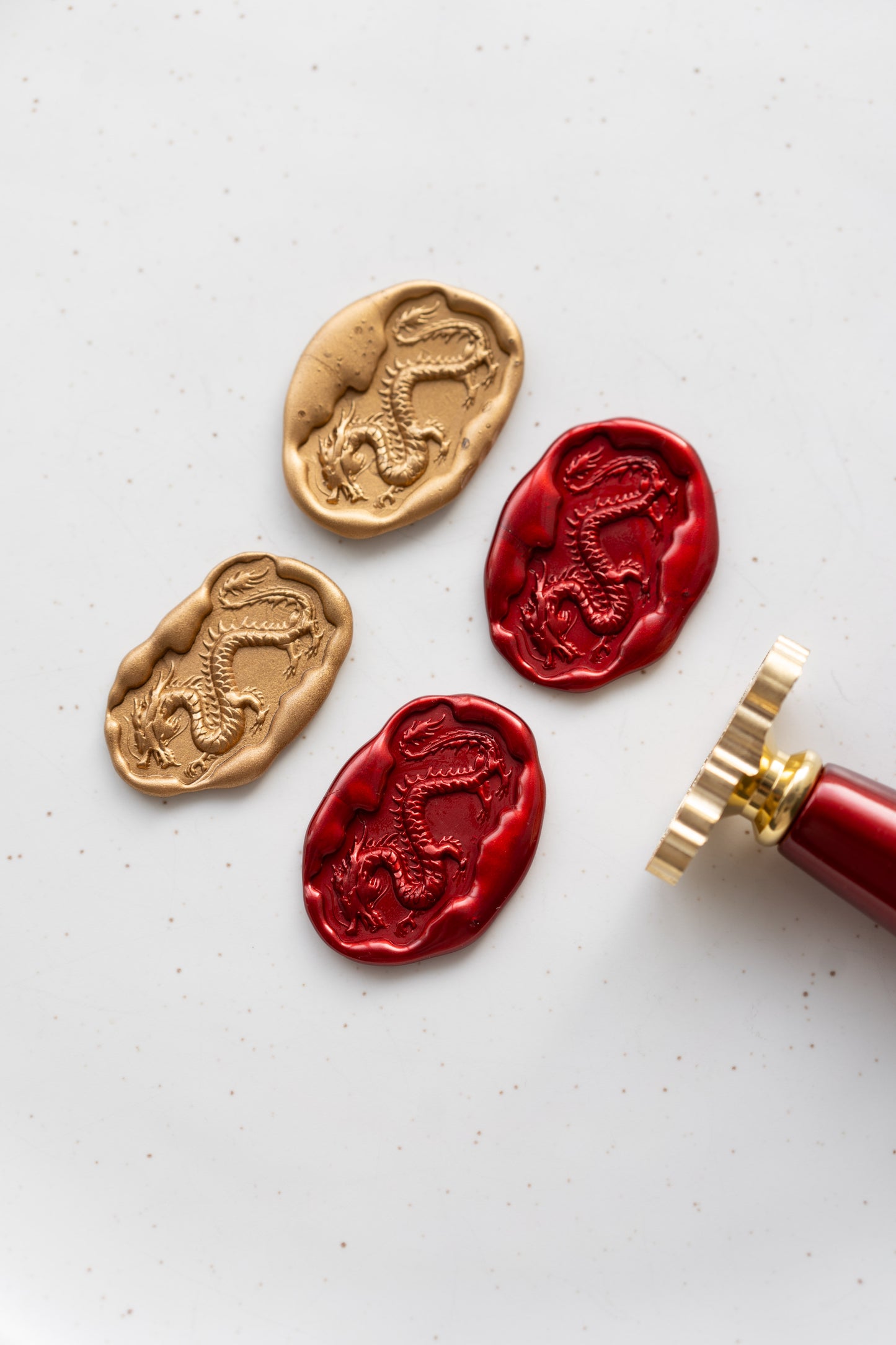 Gold and red Lunar New Year wax seals featuring an ancient dragon design, with a brass stamp with wooden handle 