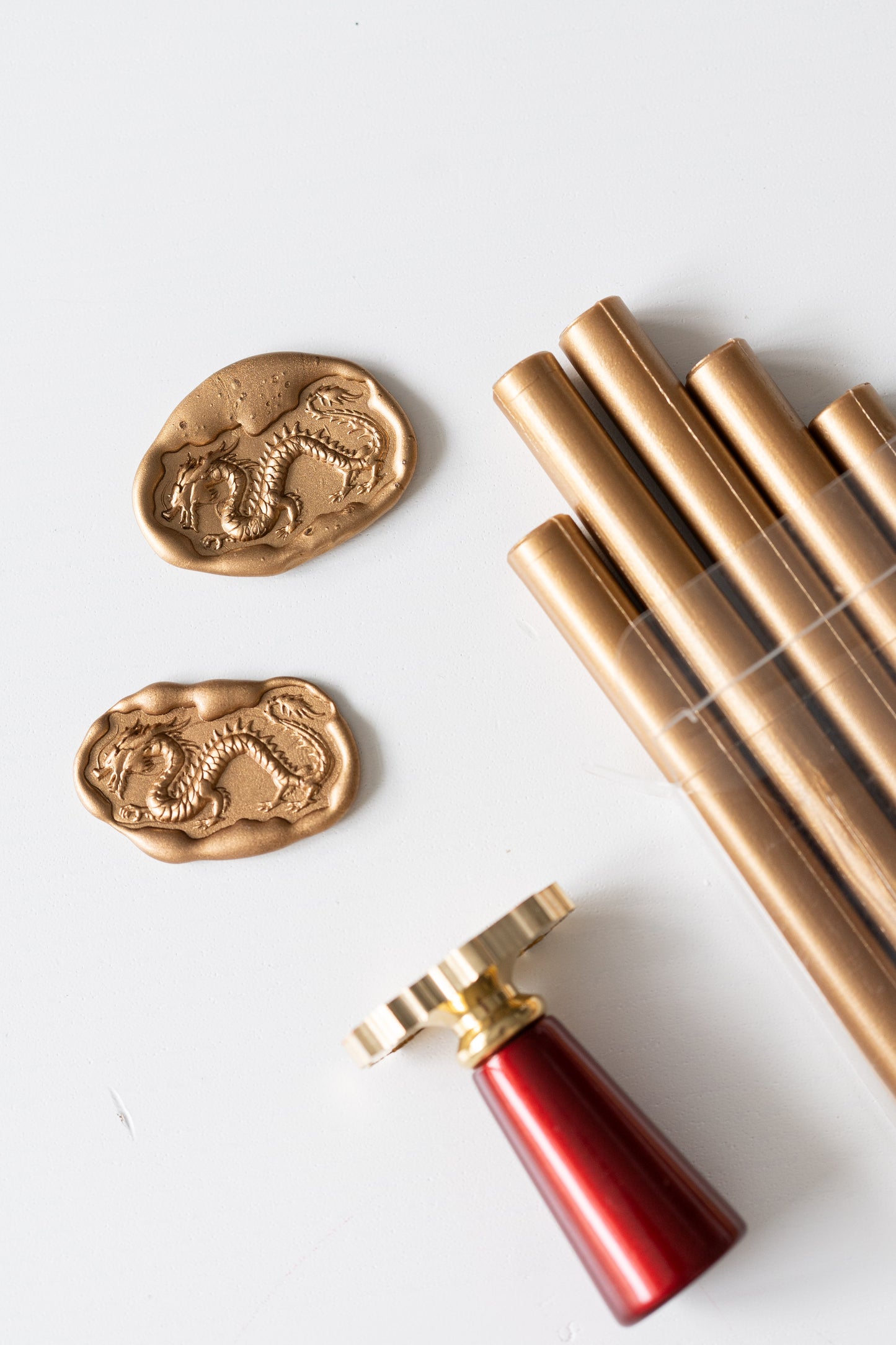 Gold Lunar New Year wax seals featuring an ancient dragon design, with a brass stamp, and gold sealing wax sticks 