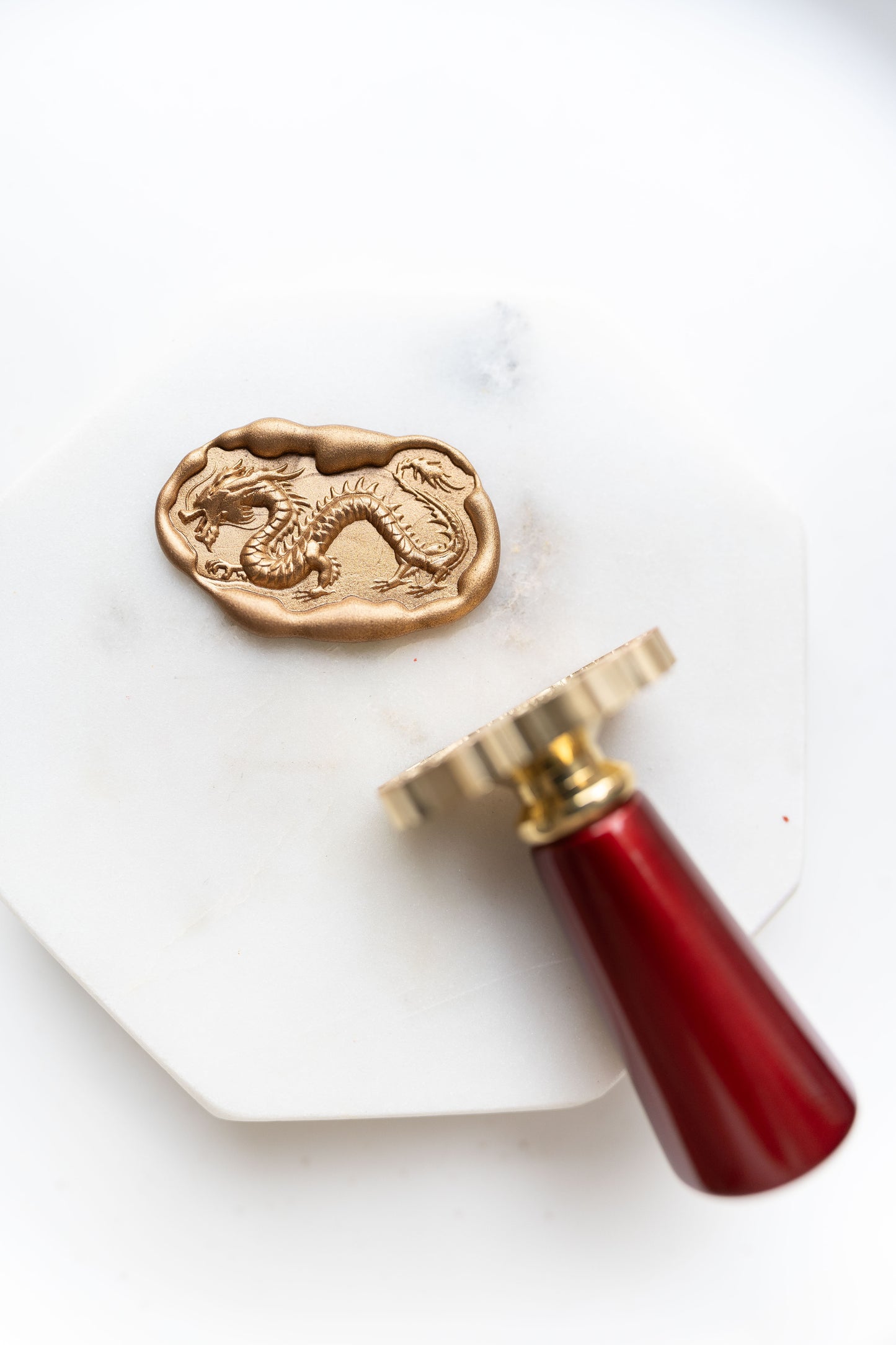A gold Lunar New Year wax seal featuring an ancient dragon design, with a brass stamp and wooden handle