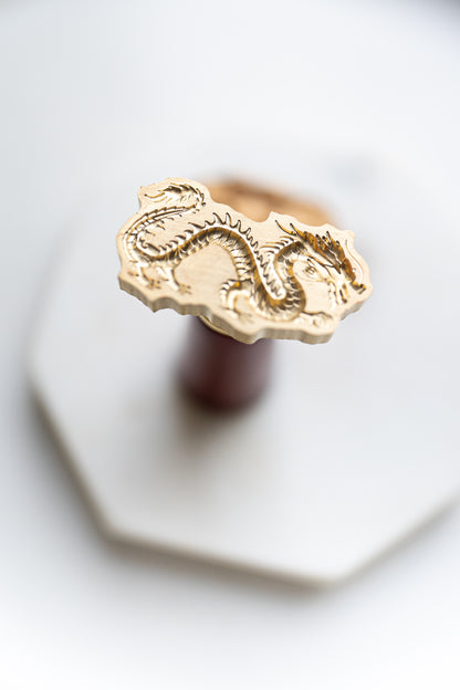 A Lunar New Year wax seal stamp featuring an ancient dragon design, styled on a marble coaster