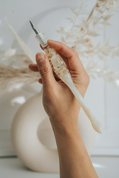 Hand holding ivory resin calligraphy pen with gold flakes, aesthetic modern calligraphy penholder