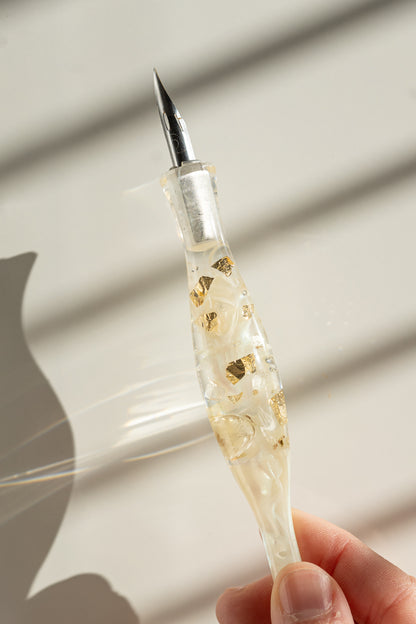 Close-up of calligraphy pen nib with ivory resin handle and gold flakes, modern calligraphy supplies detail