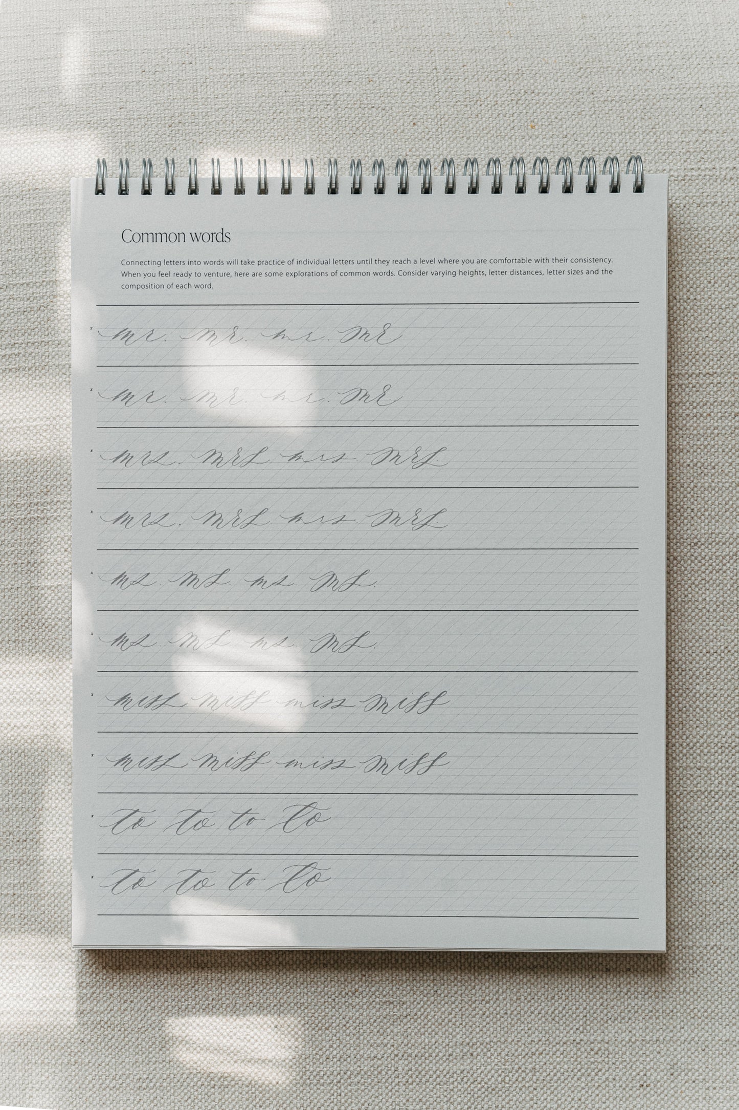 Calligraphy practice pad focusing on writing common words, with exercises for improving letter connections, spacing, and flow