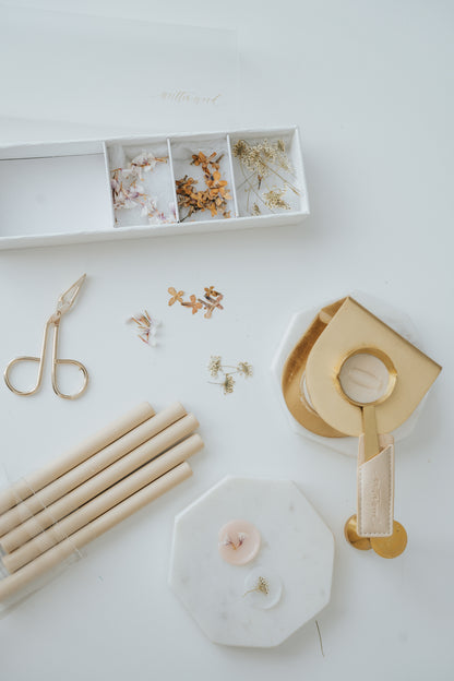 Wax Seal Floral Dust Set with dried flowers, sealing wax sticks, a brass wax seal warmer, and gold tweezers on a white surface.