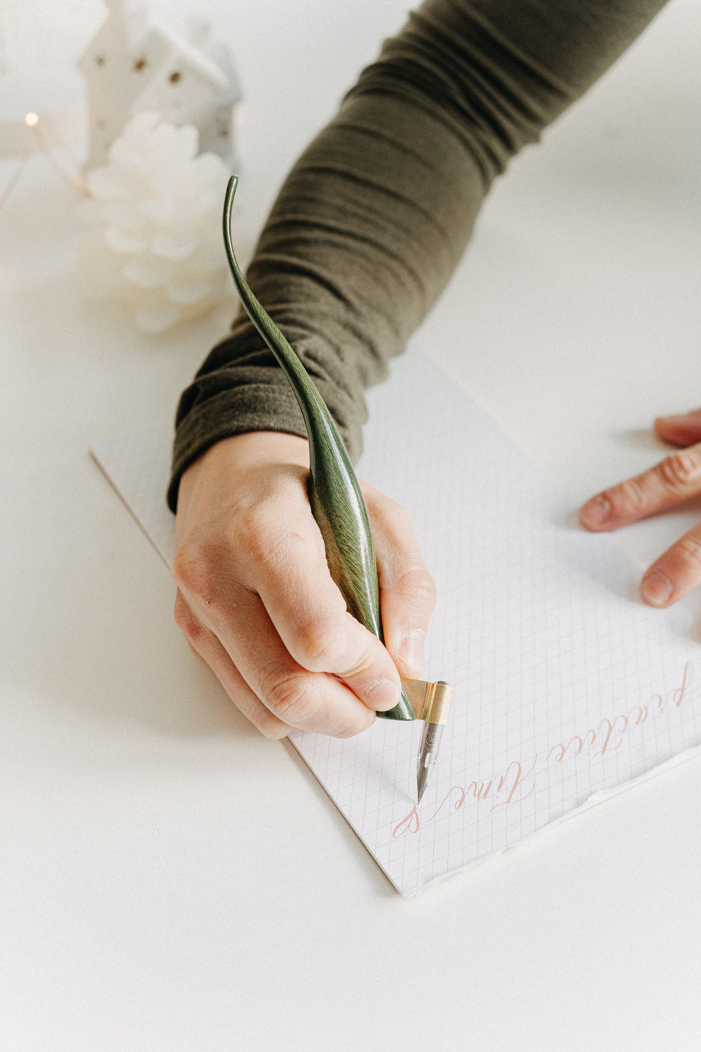 Writing “practice time” with a handcrafted green lacquer curved calligraphy penholder in a cozy holiday setting.