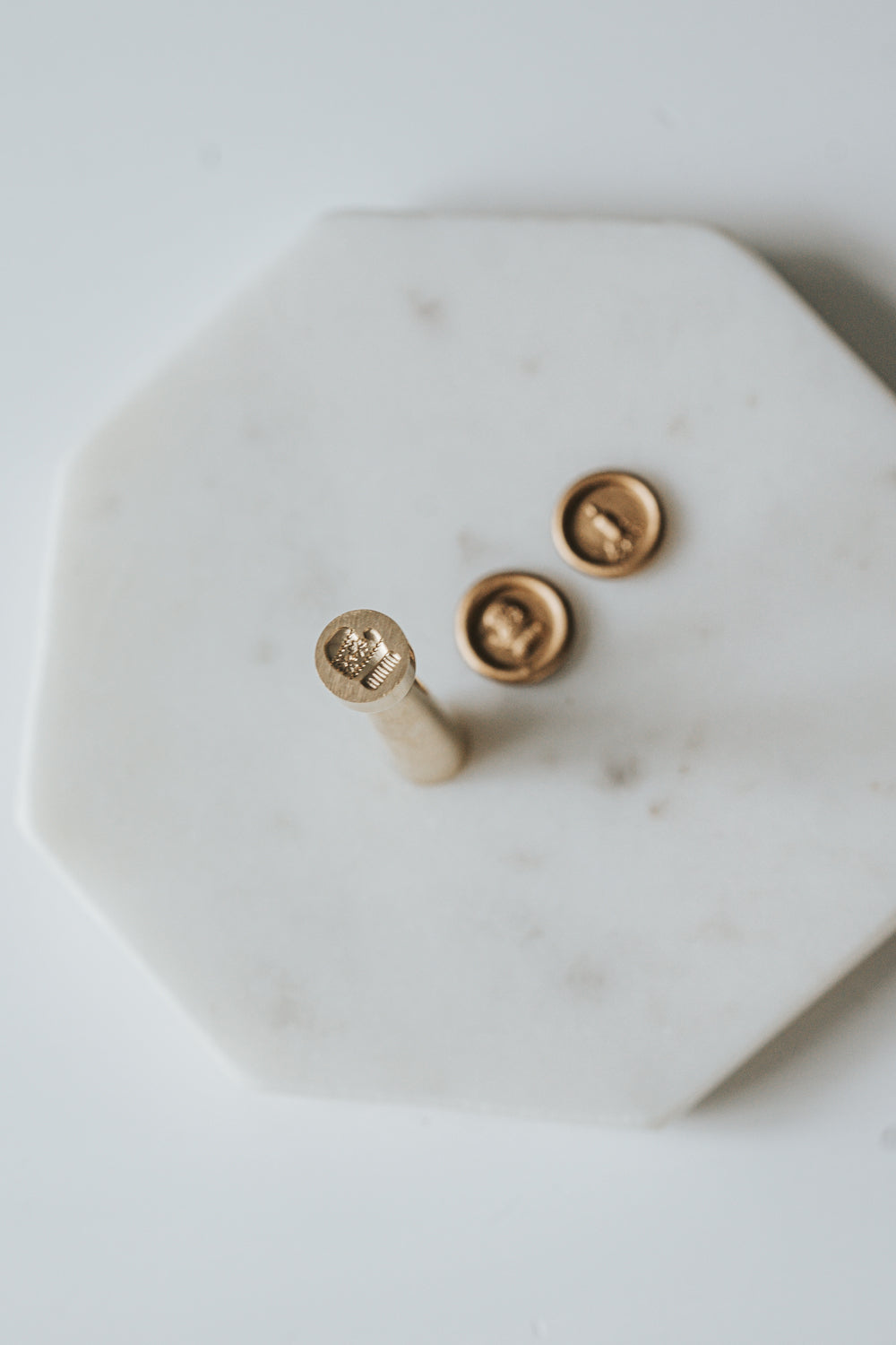 Mini wax seal stamp with a mitten design, displayed with matching gold wax seals on a white marble surface.