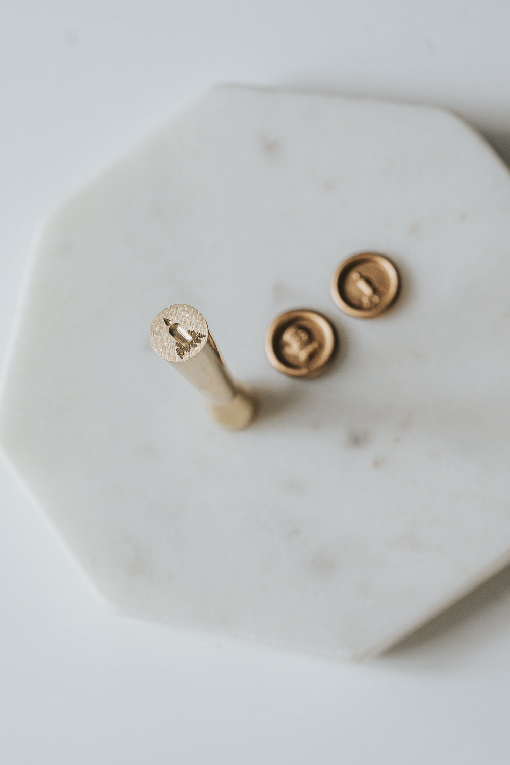 Mini wax seal stamp with a candle design, displayed with matching gold wax seals on a white marble surface.