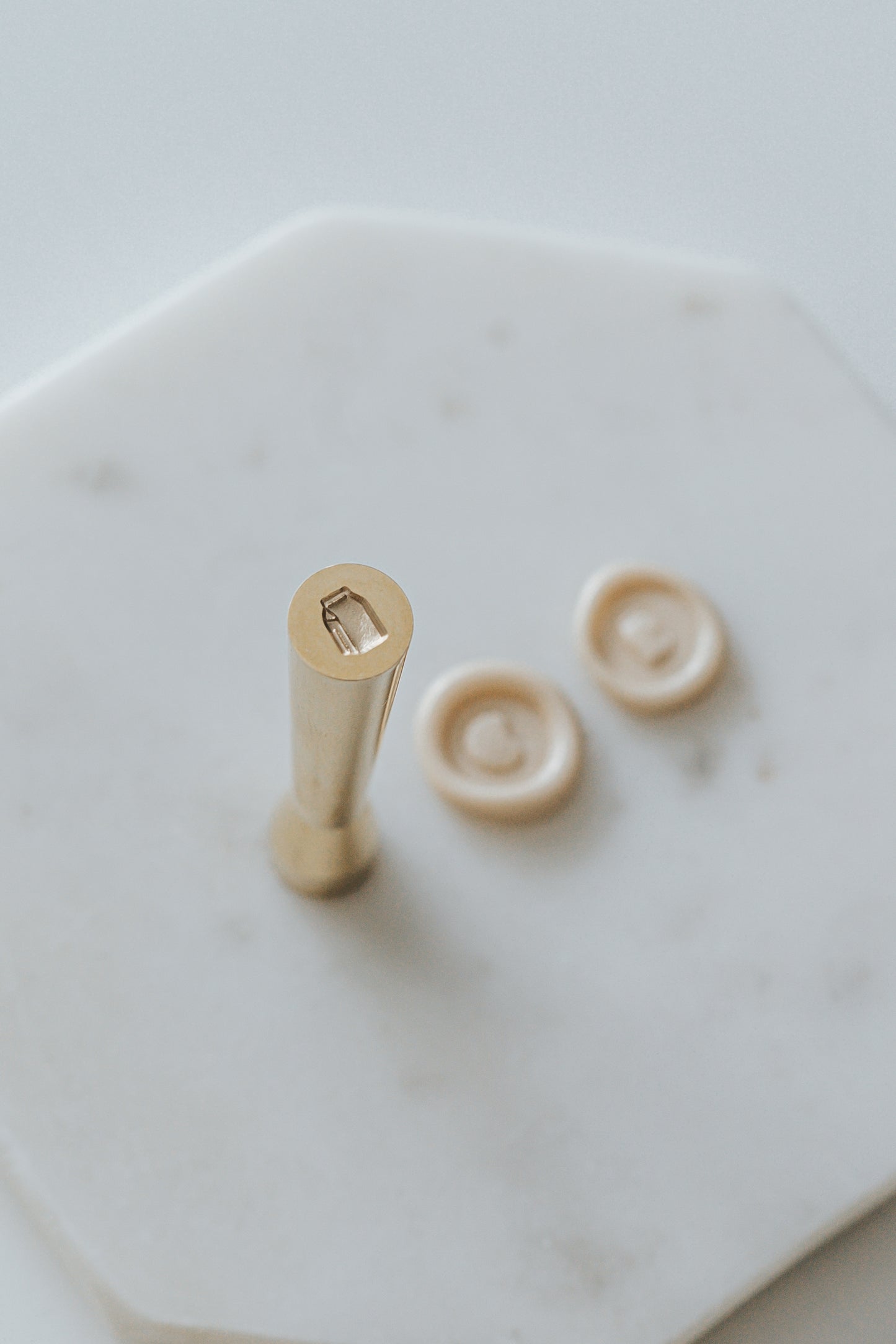 Mini wax seal stamp with a milk carton design, displayed with matching beige wax seals on a white marble surface.