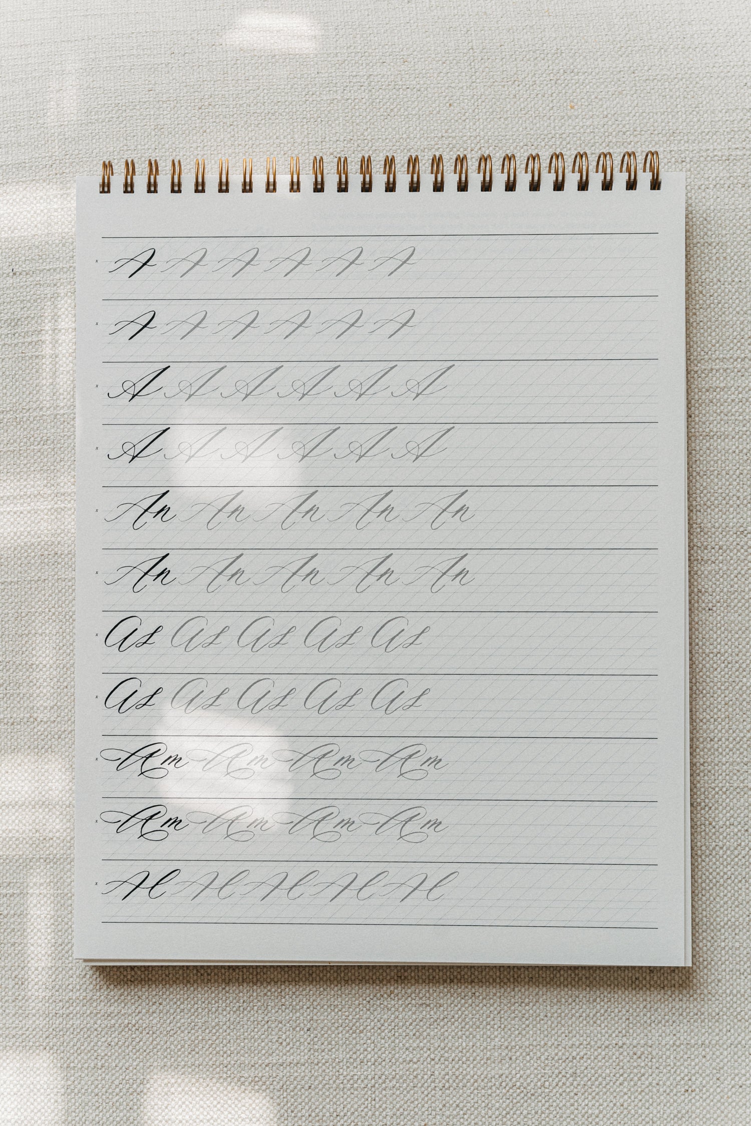 Calligraphy practice pad with drills for the letter "A," combining various letter combinations and strokes