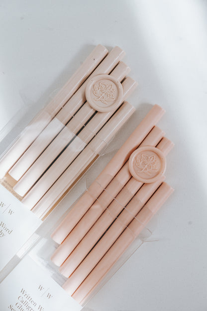 Comparison between a bundle of Sakura wax sticks and a bundle of Blush Wax Sticks with matching wax seals on a light surface