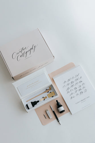 Creative Calligraphy Starter Kit with a pen, ink, nibs, workbook, and accessories, displayed on a white surface