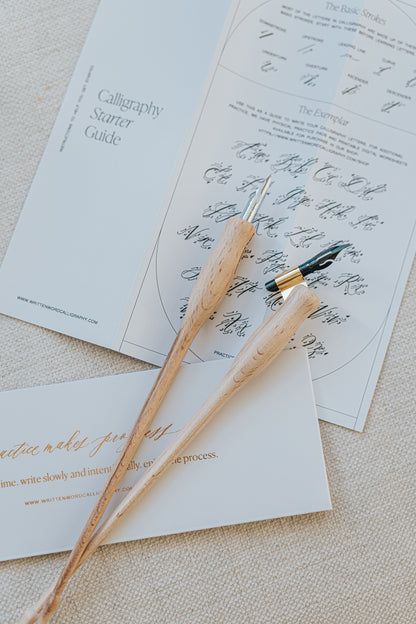 Dual-purpose calligraphy pens with nibs resting on a calligraphy guide, part of the Mini Calligraphy Starter Kit.