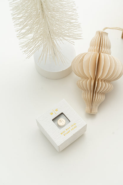 Limited edition wax seal stamp of a 3d illustration of a wrapped present with a small ribbon bow in a white ring style box.