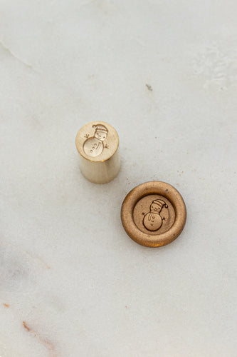 Close-up of holiday wax seal stamp featuring a snowman design in gold wax, part of Written Word Calligraphy’s Holiday Collection.