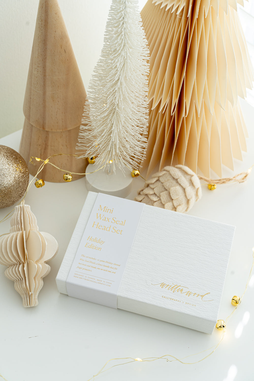 Holiday Mini Wax Seal Head Set box from Written Word Calligraphy, Holiday Edition, styled with festive neutral décor, wooden trees, and twinkle lights.