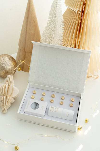 Open Holiday Mini Wax Seal Head Set from Written Word Calligraphy, featuring twelve festive brass stamp designs arranged neatly in a white gift box with soft holiday décor.