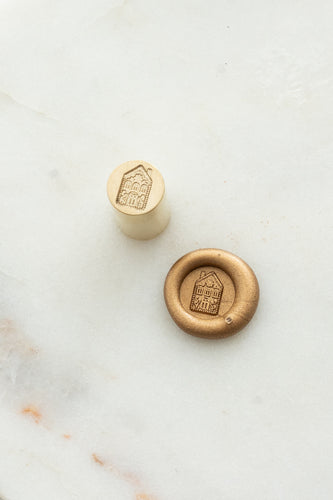 Close-up of elegant wax seal stamp featuring a gingerbread house design in gold wax, from Written Word Calligraphy’s Holiday Collection.