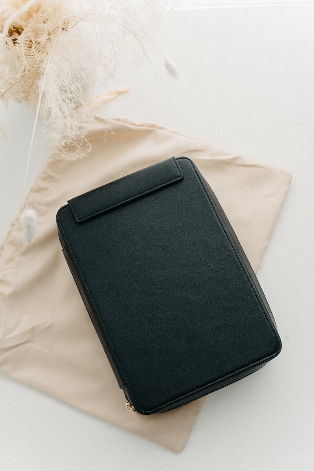 Black calligraphy travel kit on a beige dust bag on a white surface