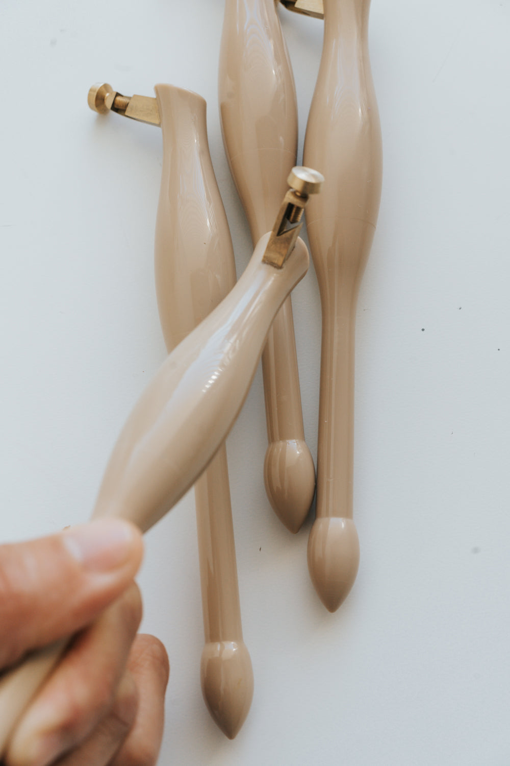 Set of beige calligraphy pens with a hand holding one, on a white background