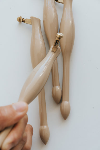 Set of beige calligraphy pens with a hand holding one, on a white background