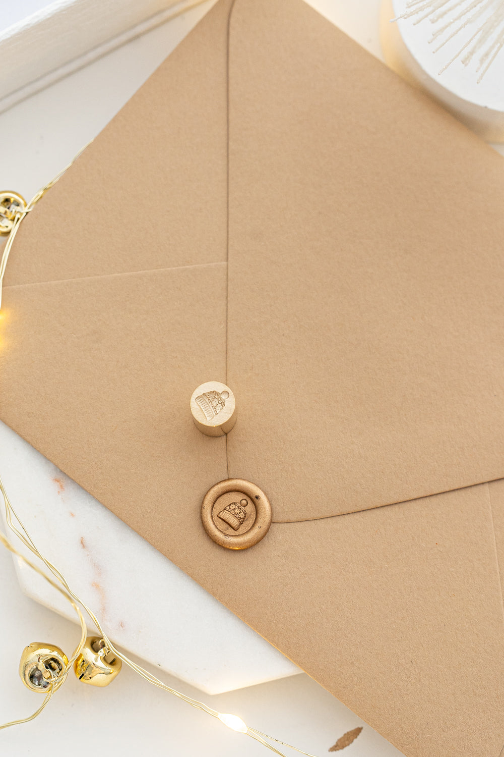 Mini wax seal stamp with a cozy toque design in gold wax on a kraft envelope, part of Written Word Calligraphy’s Holiday Collection.
