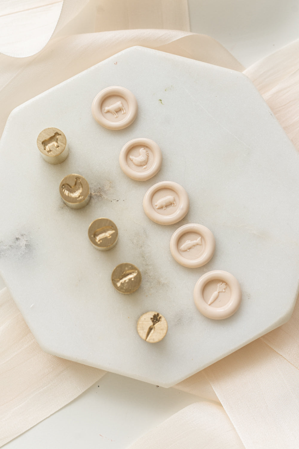 Set of mini wax seal heads with entrée option designs on a marble surface