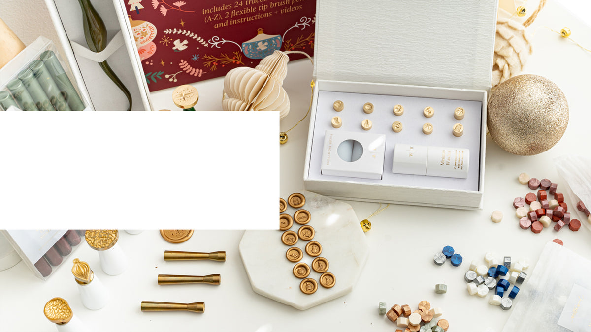 Mini wax seal holiday collection gift set with interchangeable brass stamp heads, sealing wax, and festive accessories.