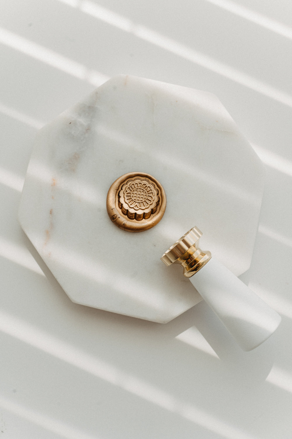 Gold mooncake wax seal stamp with floral brass head on white marble tray for Mid-Autumn Festival