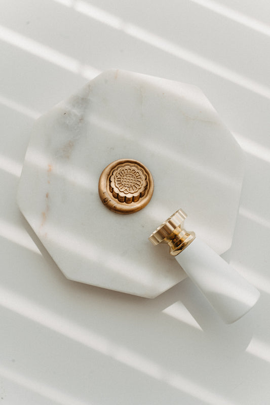 Gold mooncake wax seal stamp with floral brass head on white marble tray for Mid-Autumn Festival
