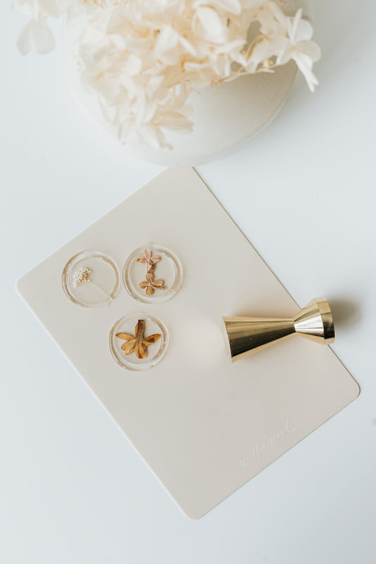 Floral wax seals on silicone mat with brass wax seal stamp and dried flowers above