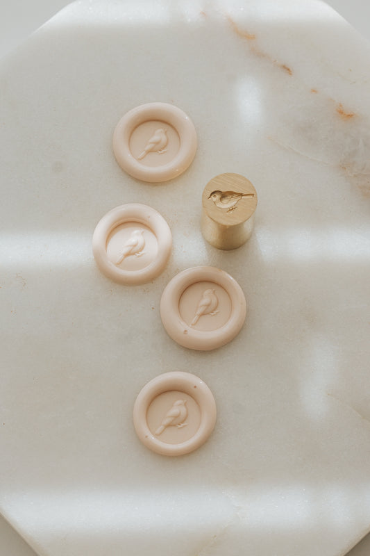 Sakura songbird wax seal impressions with brass stamp on marble surface