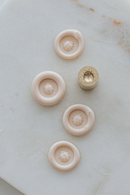 Multiple sakura ladybug wax seal impressions with brass stamp