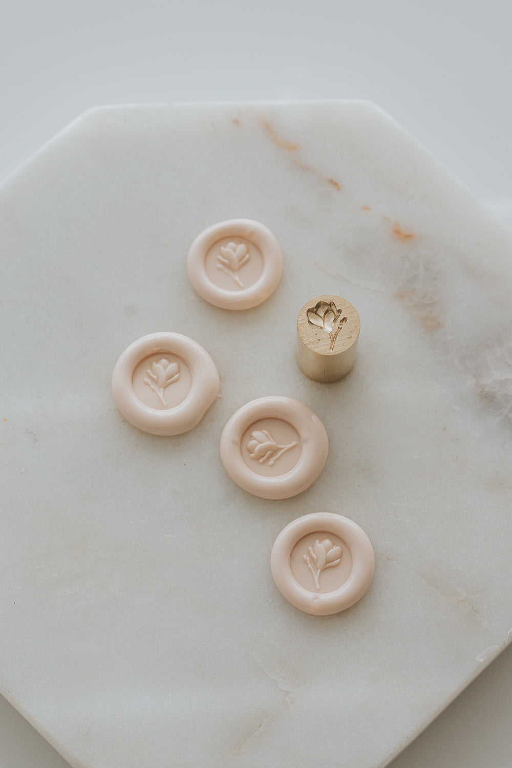 Multiple sakura magnolia bud wax seal impressions with brass stamp on marble background