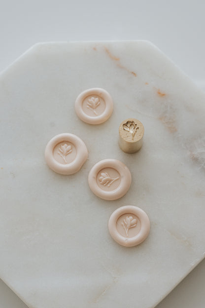 Multiple sakura magnolia bud wax seal impressions with brass stamp on marble background