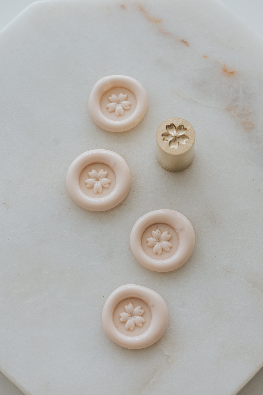 Multiple cherry blossom wax seal impressions with mini brass stamp on marble