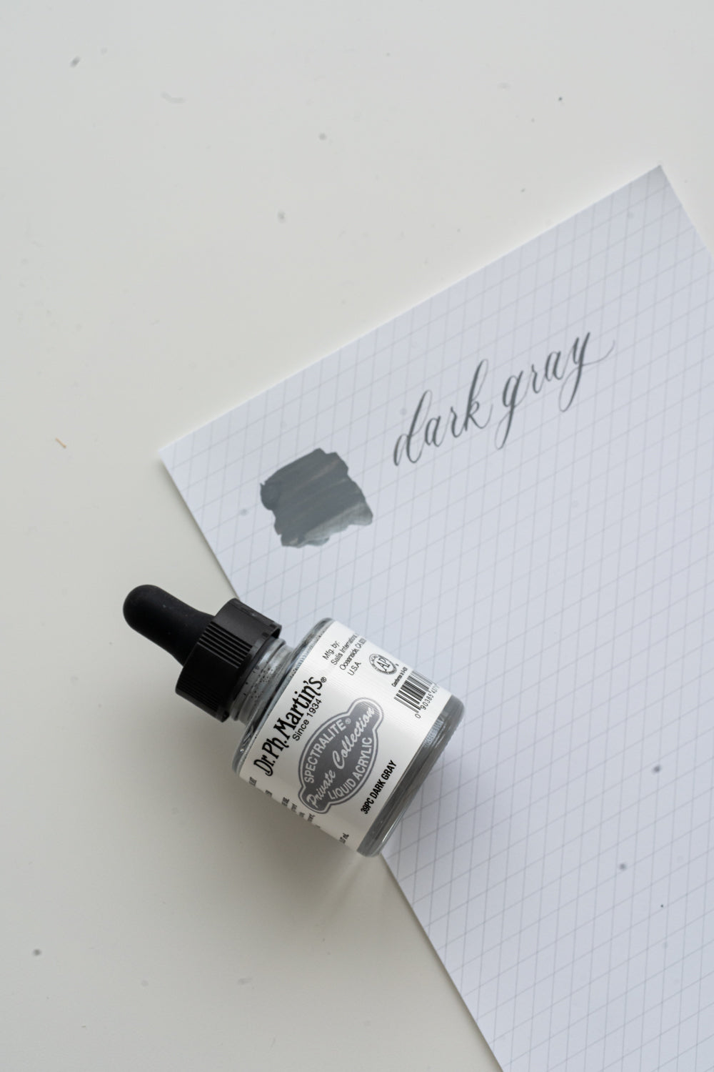 Dr Ph Martin’s dark gray calligraphy ink bottle with swatch on grid paper, modern calligraphy ink supplies