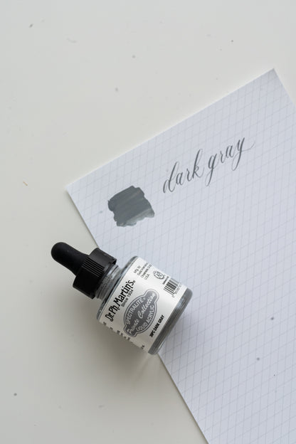 Dr Ph Martin’s dark gray calligraphy ink bottle with swatch on grid paper, modern calligraphy ink supplies