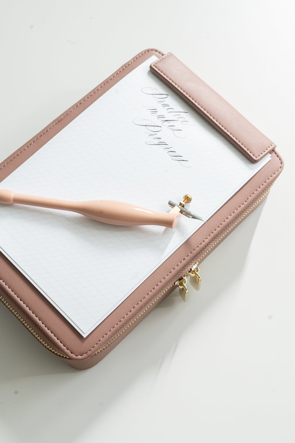 Calligraphy practice pad clipped into dusty rose travel case with oblique pen for modern calligraphy practice