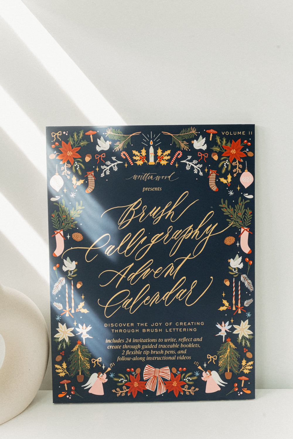 Front view of Brush Calligraphy Advent Calendar Volume II, a Christmas brush lettering kit with 24 creative prompts.