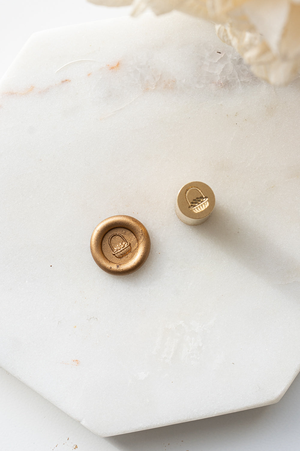 A close-up of the limited edition mini wax seal stamp with a 3d illustration of a basket of eggs